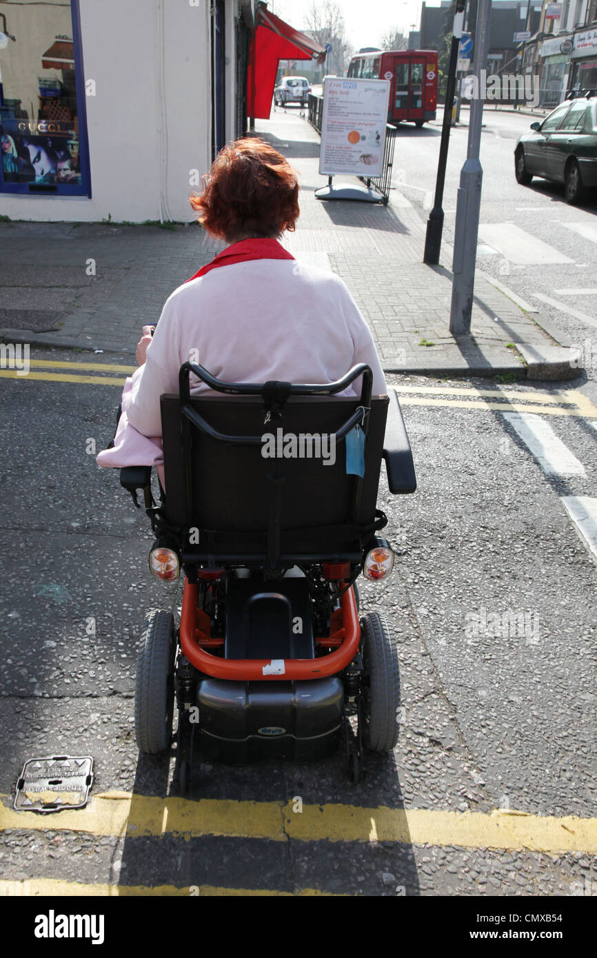 Elektro-Rollstuhl Benutzer fahren auf eine eine angepasste Pflaster Stockfoto