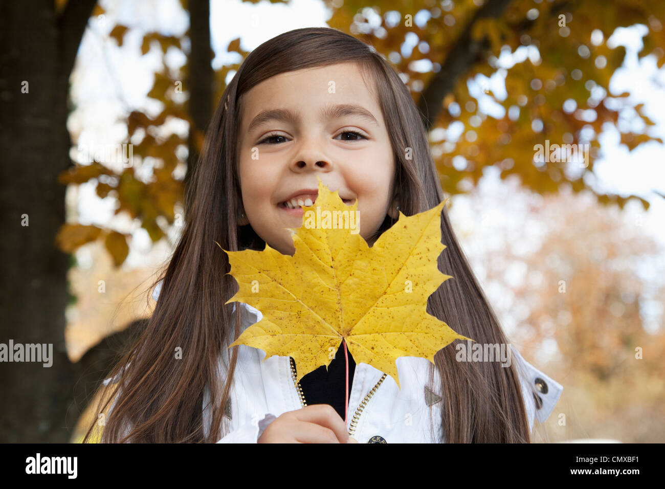 Deutschland, Huglfing, Mädchen Blatt halten, Lächeln, Porträt Stockfoto