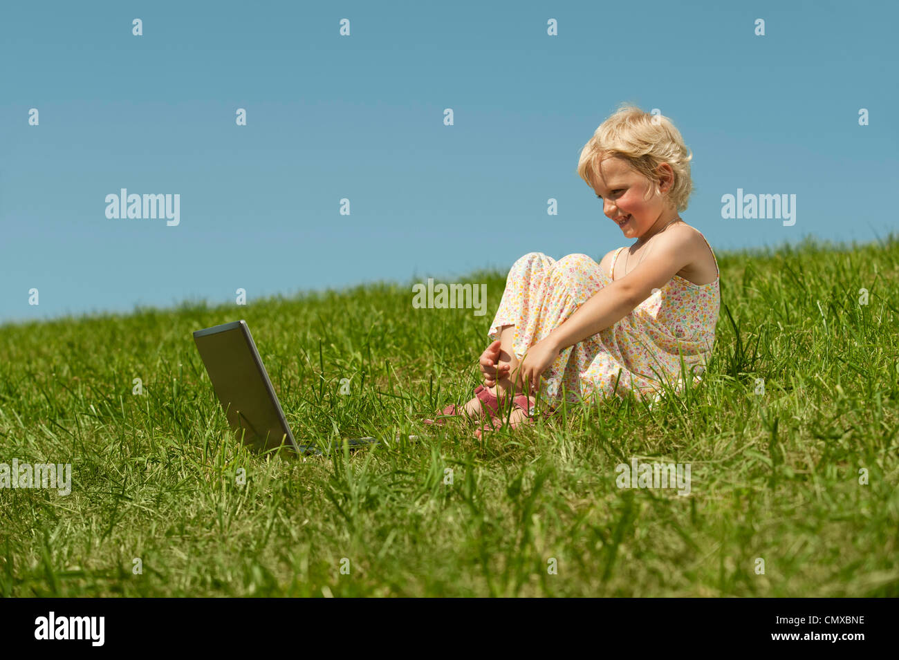 Deutschland, Bayern, Mädchen mit Laptop sitzen in Rasen Stockfoto