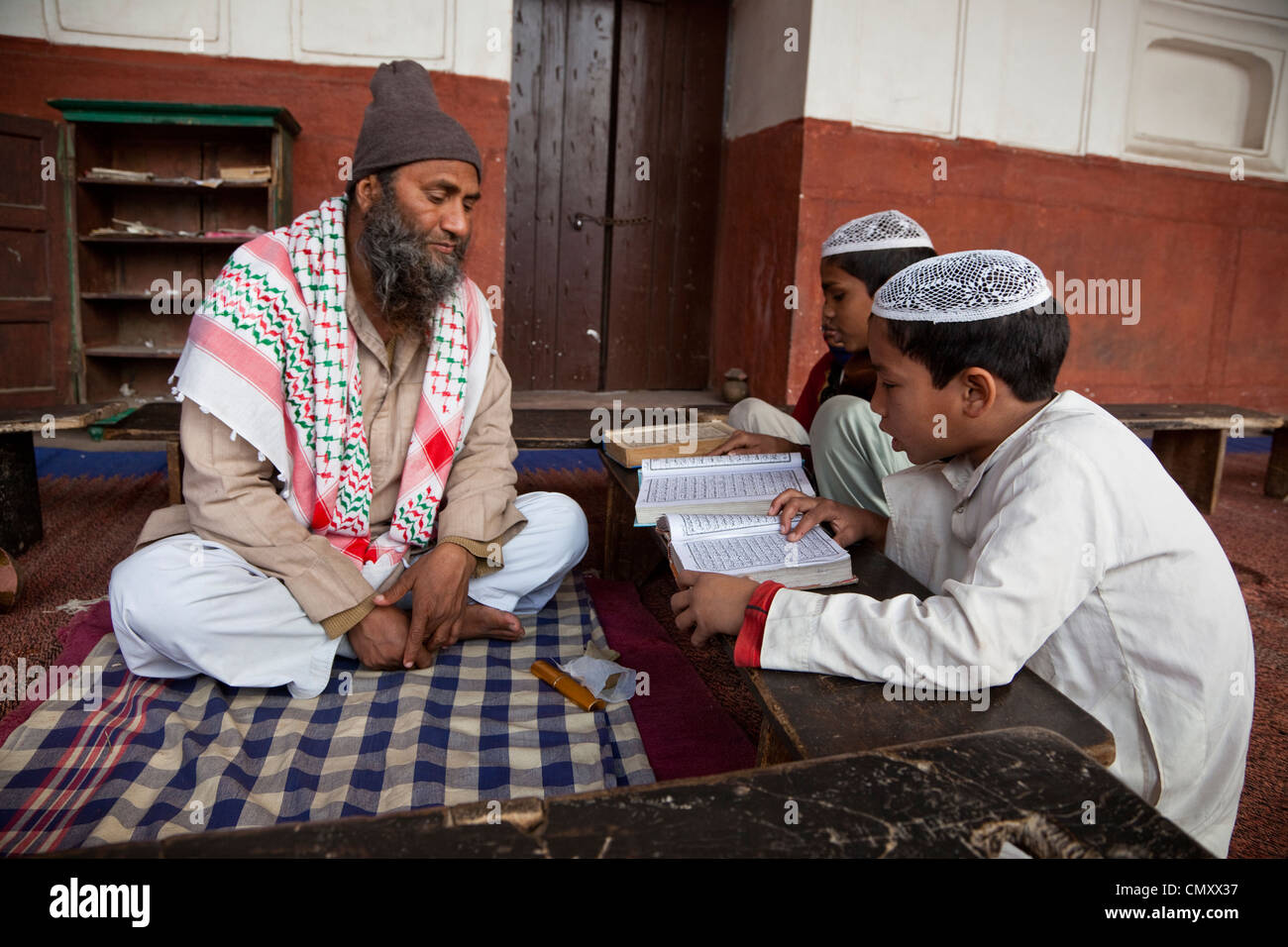 Agra, Indien. Schüler lernen, den Koran mit ihrem Imam zu lesen. Stockfoto