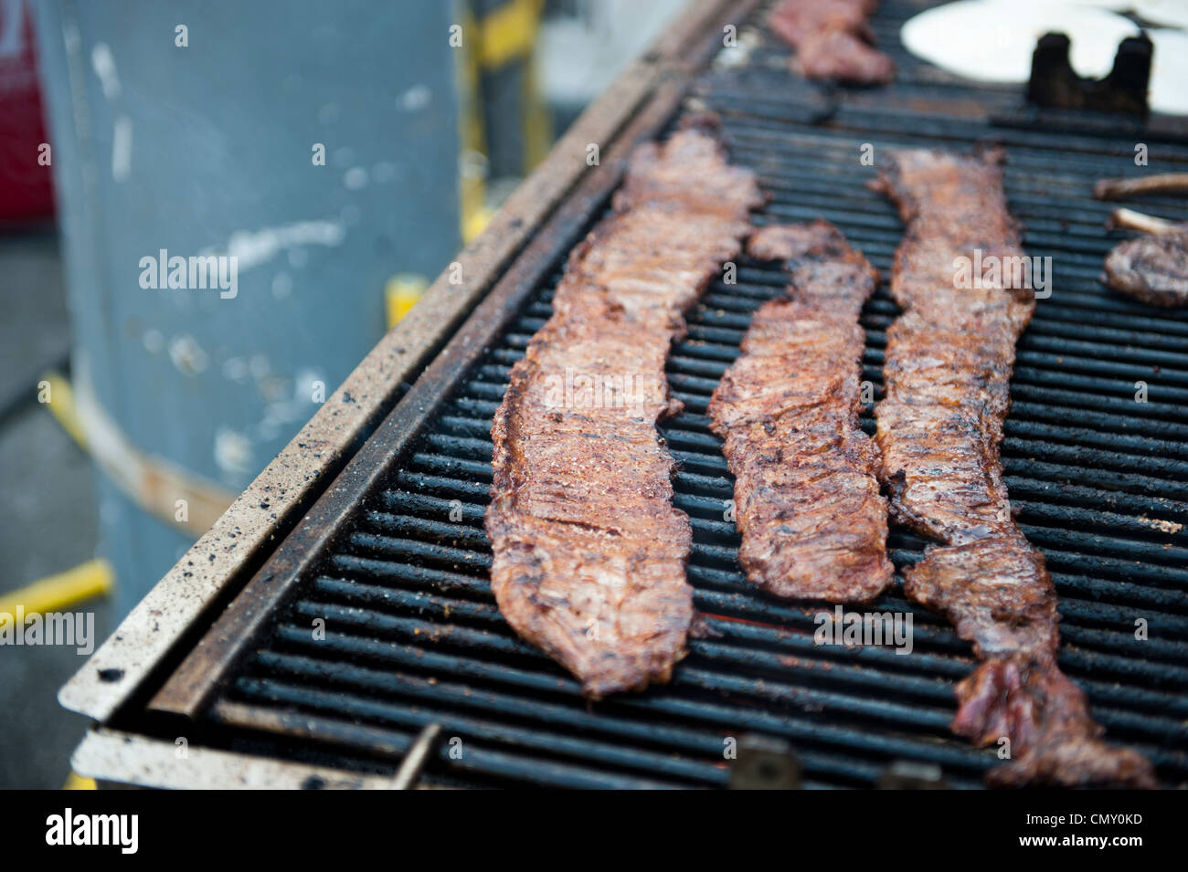 Drei Scheiben Bacon nebeneinander ausgekleidet und Kochen auf dem Grill. Stockfoto