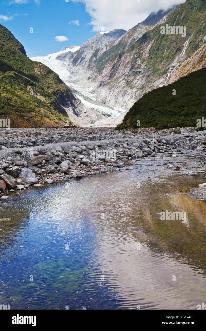 Franz Josef Glacier, West Coast, New Zealand, spiegelt sich in einem Bach im Tal. Stockfoto