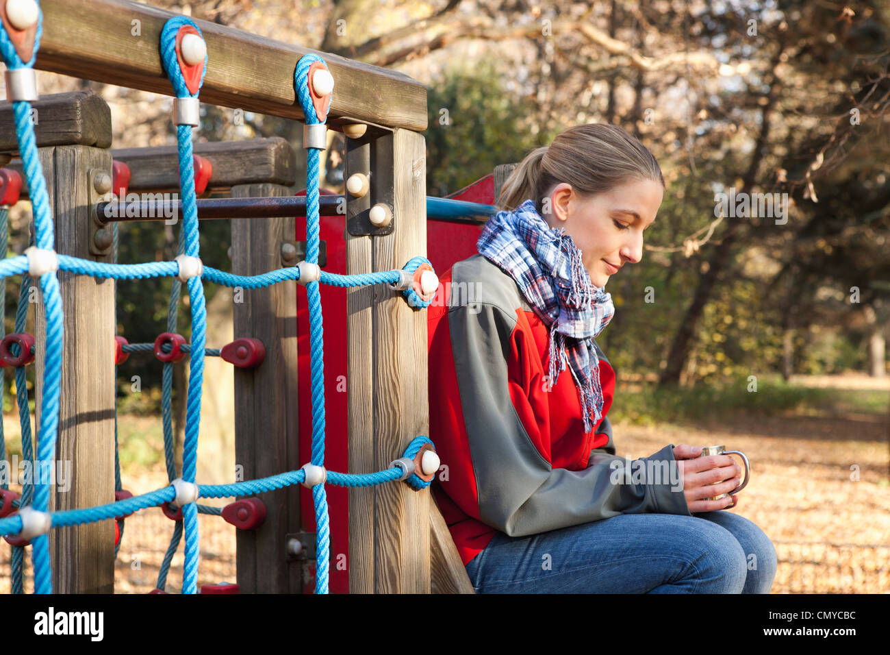 Deutschland, Berlin, Wandlitz, Mitte erwachsenen Frau trinkt Kaffee am Spielplatz Stockfoto