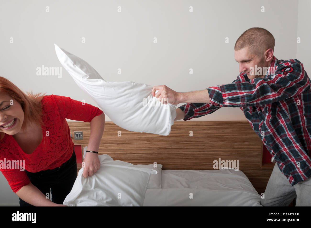 Junges Paar mit verspielten Kissen kämpfen im Hotelzimmer. Stockfoto