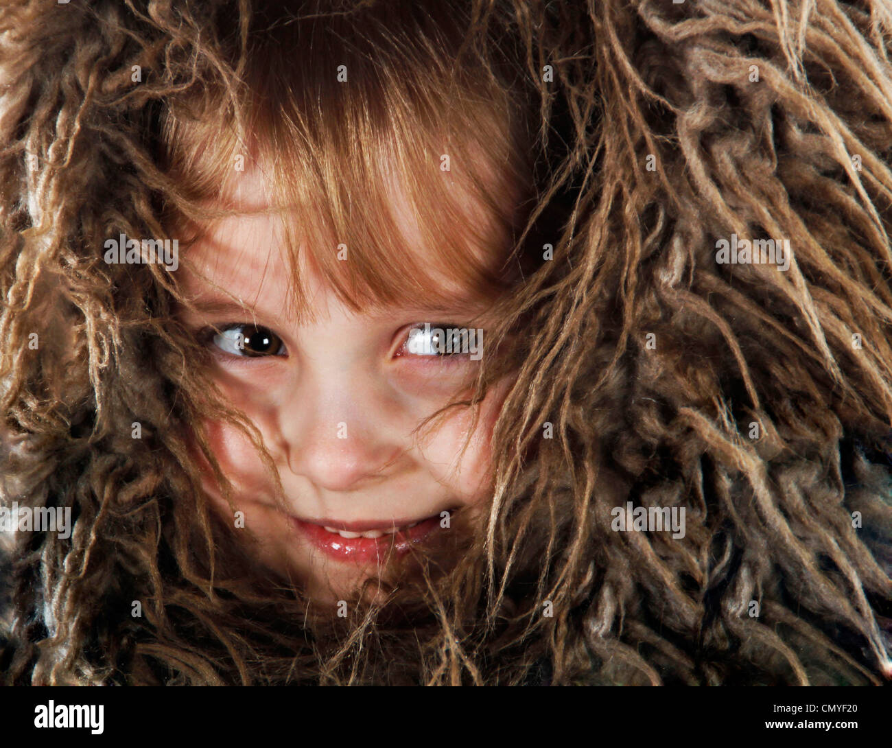 Fotografie eines Kindes süß und schüchtern mit Fell rund um Gesicht versteckt sich vor der Kamera hautnah Stockfoto