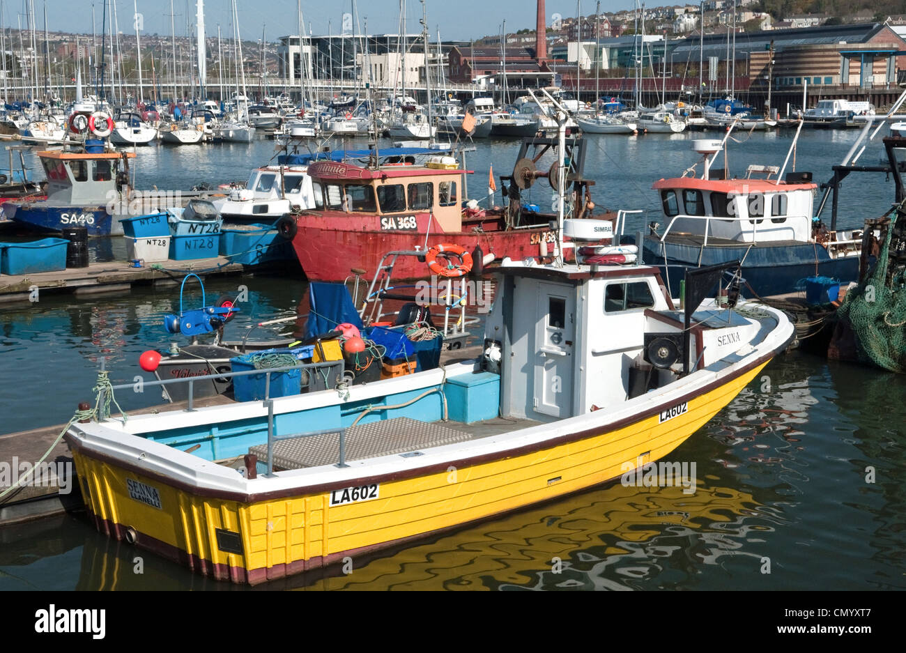 Angelboote/Fischerboote vertäut im Fischerviertel von South Wales Swansea Marina mit einem sehr prominenten gelben Boot im Vordergrund. Stockfoto