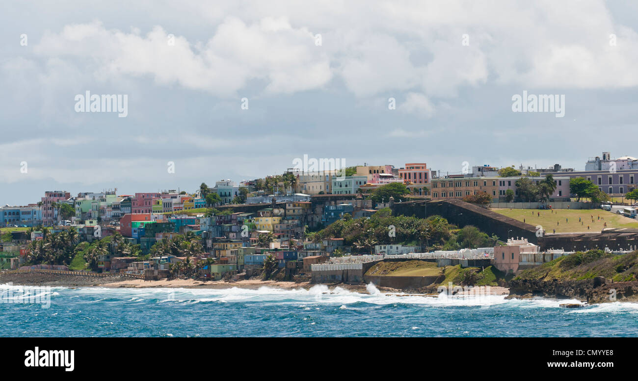Bunte Häuser und Gebäude drängen sich am Hang entlang der Küste auf dem Ansatz zum Hafen von San Juan in Puerto Rico. Stockfoto
