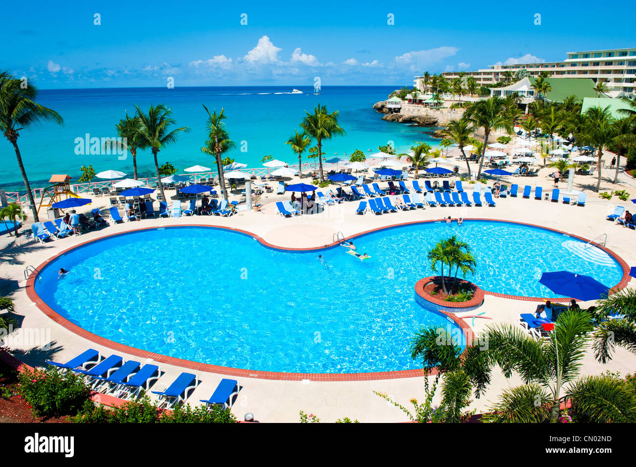 Ein Schuss getroffen vom Balkon einer Ferienanlage einen Poolbereich; die Aufnahme bietet auch einen schönen Blick auf das tiefblaue Meer. Stockfoto