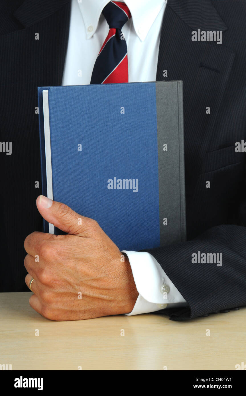 Nahaufnahme eines Geschäftsmannes, der ein Buch hält an seinem Schreibtisch. Stockfoto
