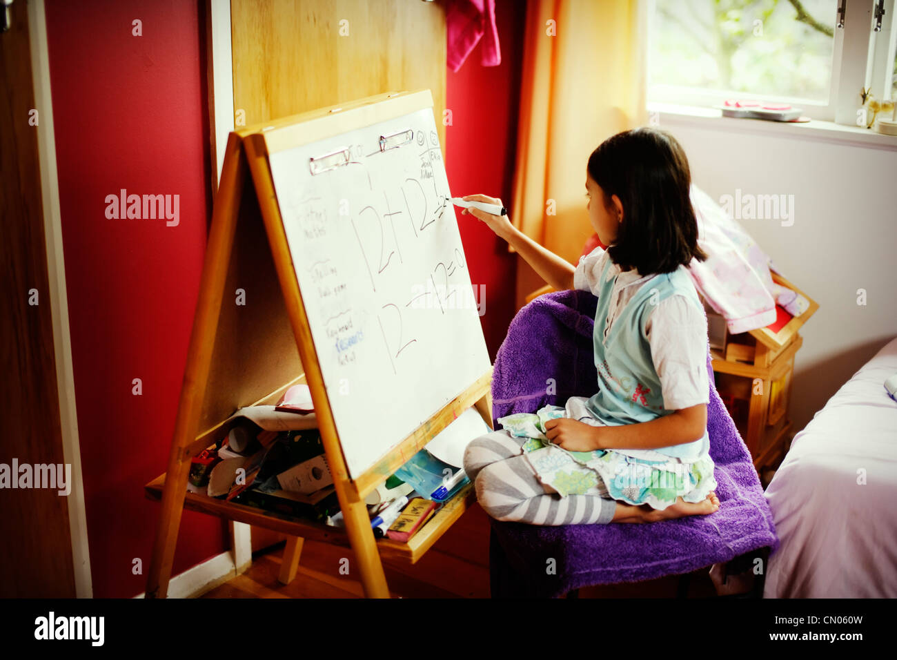 Mädchen schreibt Matheaufgaben auf Whiteboard. Stockfoto