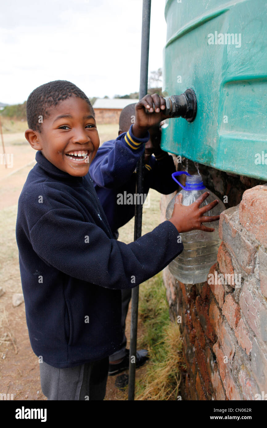 Studenten sammeln Wasser für den Unterricht aus einem Tank installiert auf ihrem Spielplatz. Hlau Hlau, Mpumalanga, Südafrika Stockfoto