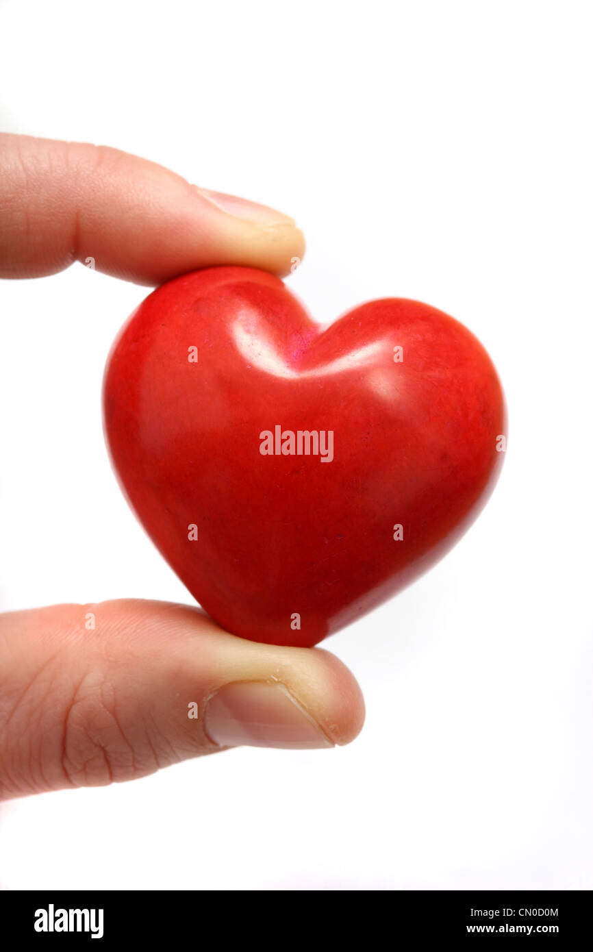Symbolisches Bild, Herz-Kreislauferkrankungen, Herzinfarkt, Schutz, Prävention, Kardiologie. Hände halten ein rotes Herz. Stockfoto