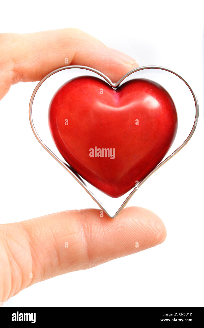 Symbolisches Bild, Herz-Kreislauferkrankungen, Herzinfarkt, Schutz, Prävention, Kardiologie. Hände halten ein rotes Herz. Stockfoto