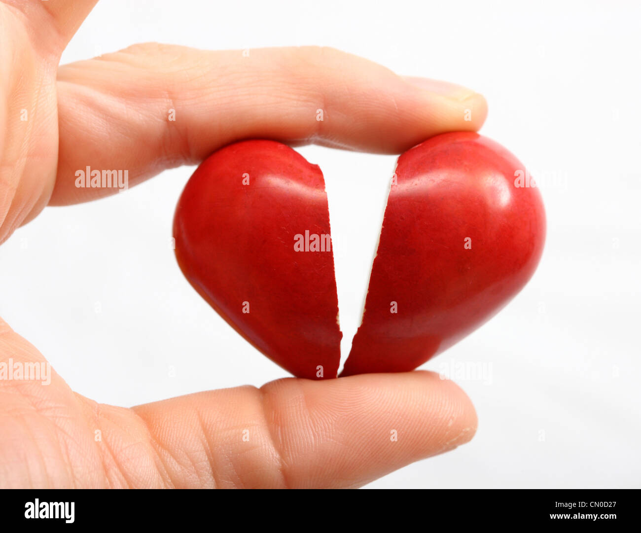 Symbolisches Bild, Herz-Kreislauferkrankungen, Herzinfarkt, Schutz, Prävention, Kardiologie. Hände halten ein gebrochenes rotes Herz in 2 Stücke. Stockfoto