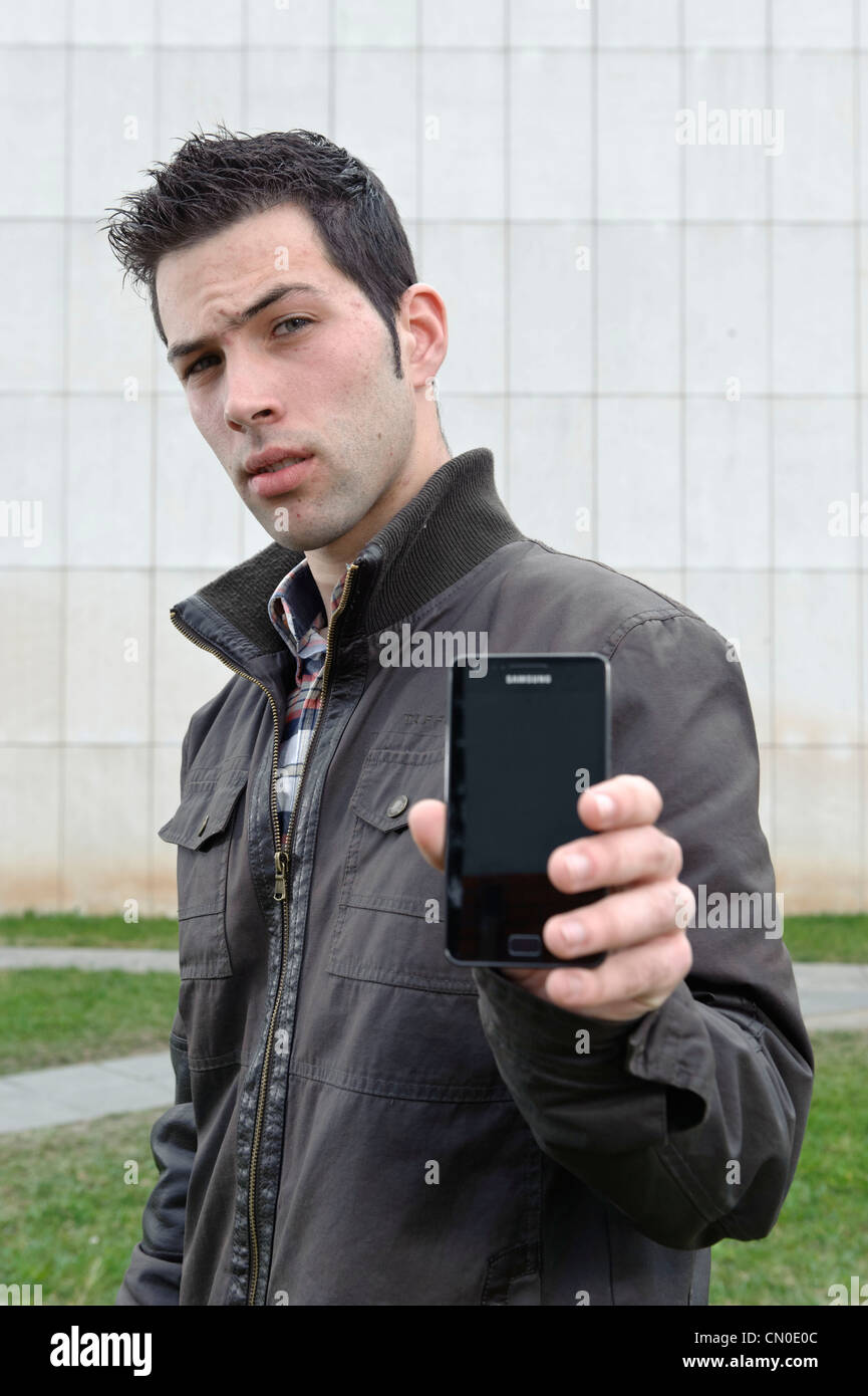 Junger Mann hält Samsung smartphone Stockfoto