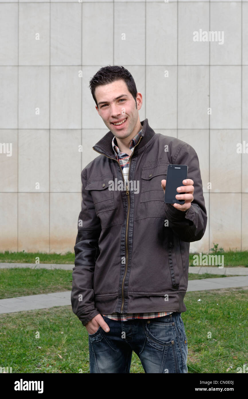 Junger Mann hält Samsung smartphone Stockfoto
