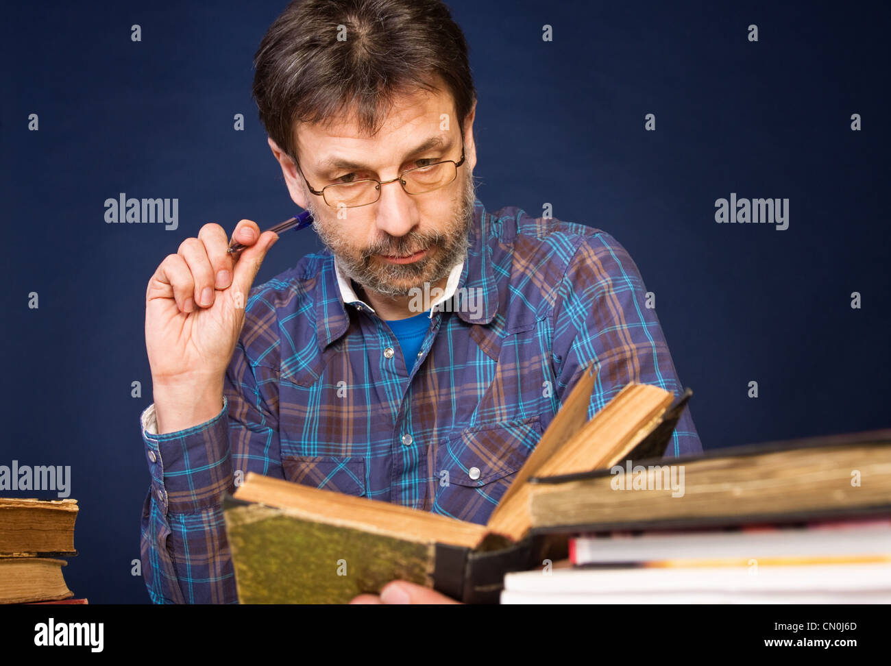 Reifer Mann in Gläsern, die Lektüre seines Buches Stockfoto