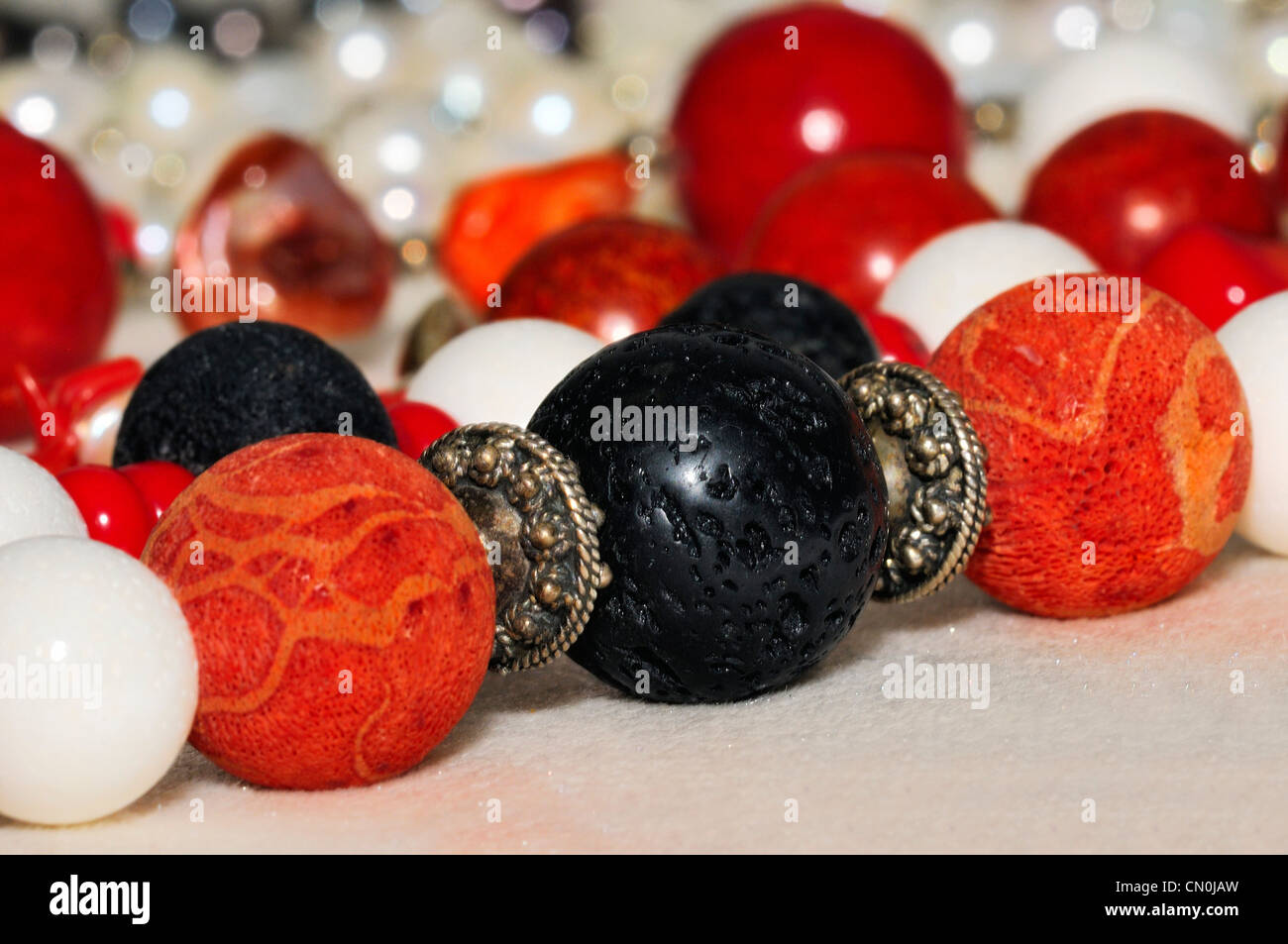 Ein schwarzer Lava Stein zwischen zwei Korallen Perlen an einer Hand gearbeitete Halskette auf einer Kunstmesse aufgereiht. Stockfoto