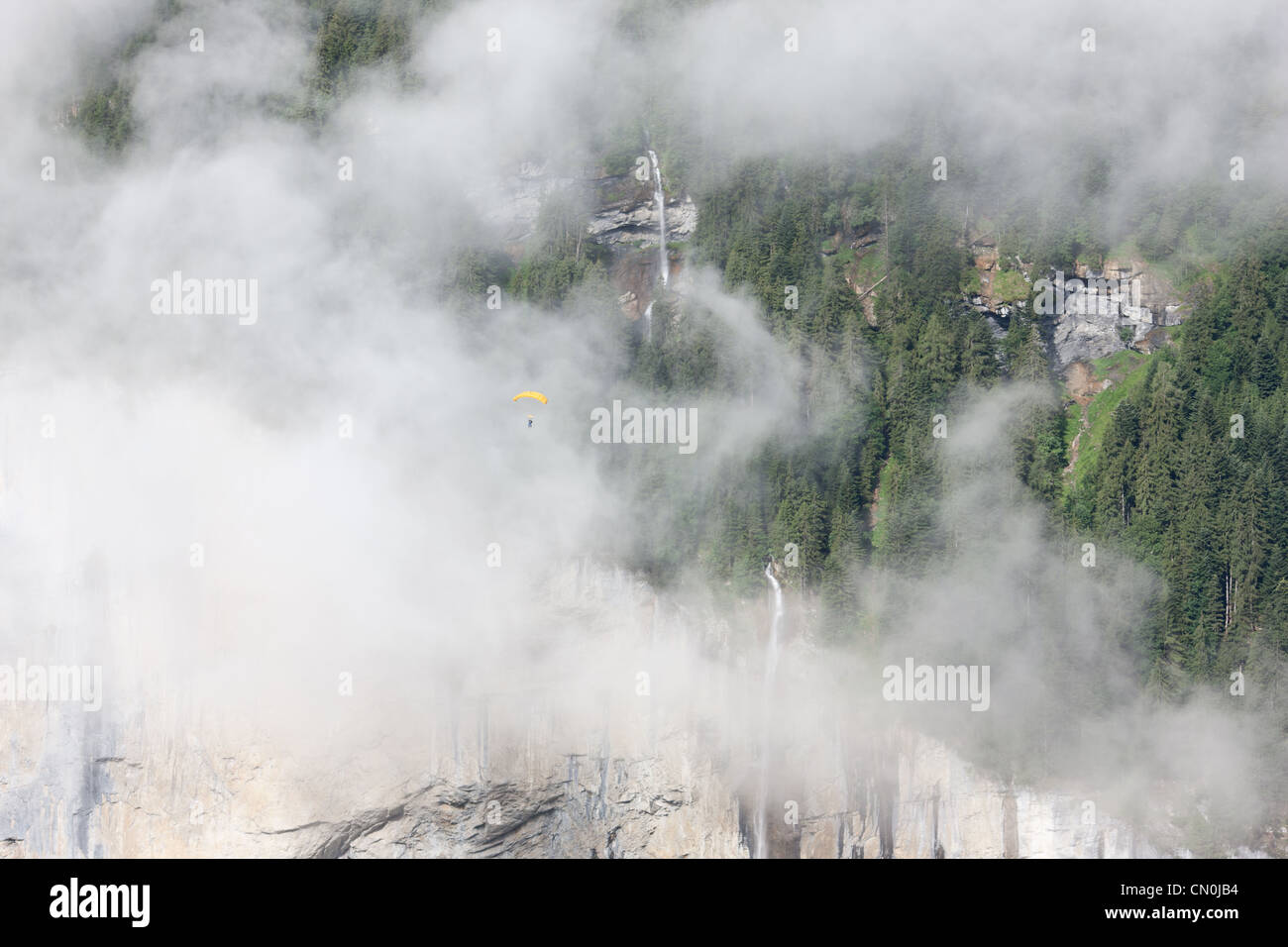 Fallschirmspringer / Fallschirmspringer, der durch einen von Nebel umhüllten Wasserfall aufsteigt. Staubbachfall, Lauterbrunnental, Bern, Schweiz. Stockfoto