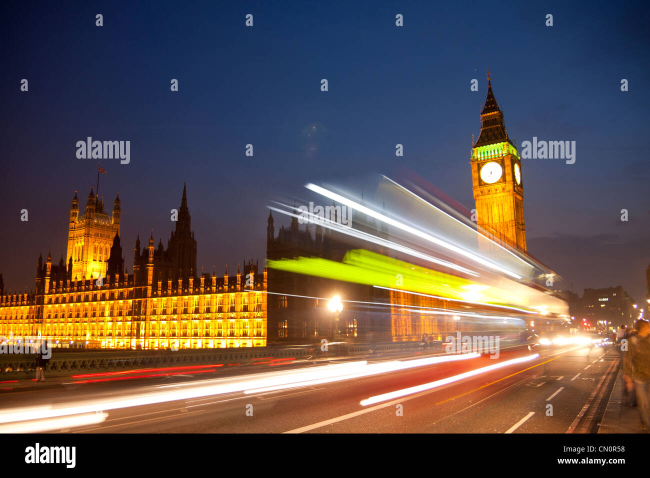 Big Ben Clock Tower Houses of Parliament in der Nacht mit verschwommenen Lichtern der vorbeifahrenden roten Londoner Bus im Vordergrund London England UK Stockfoto