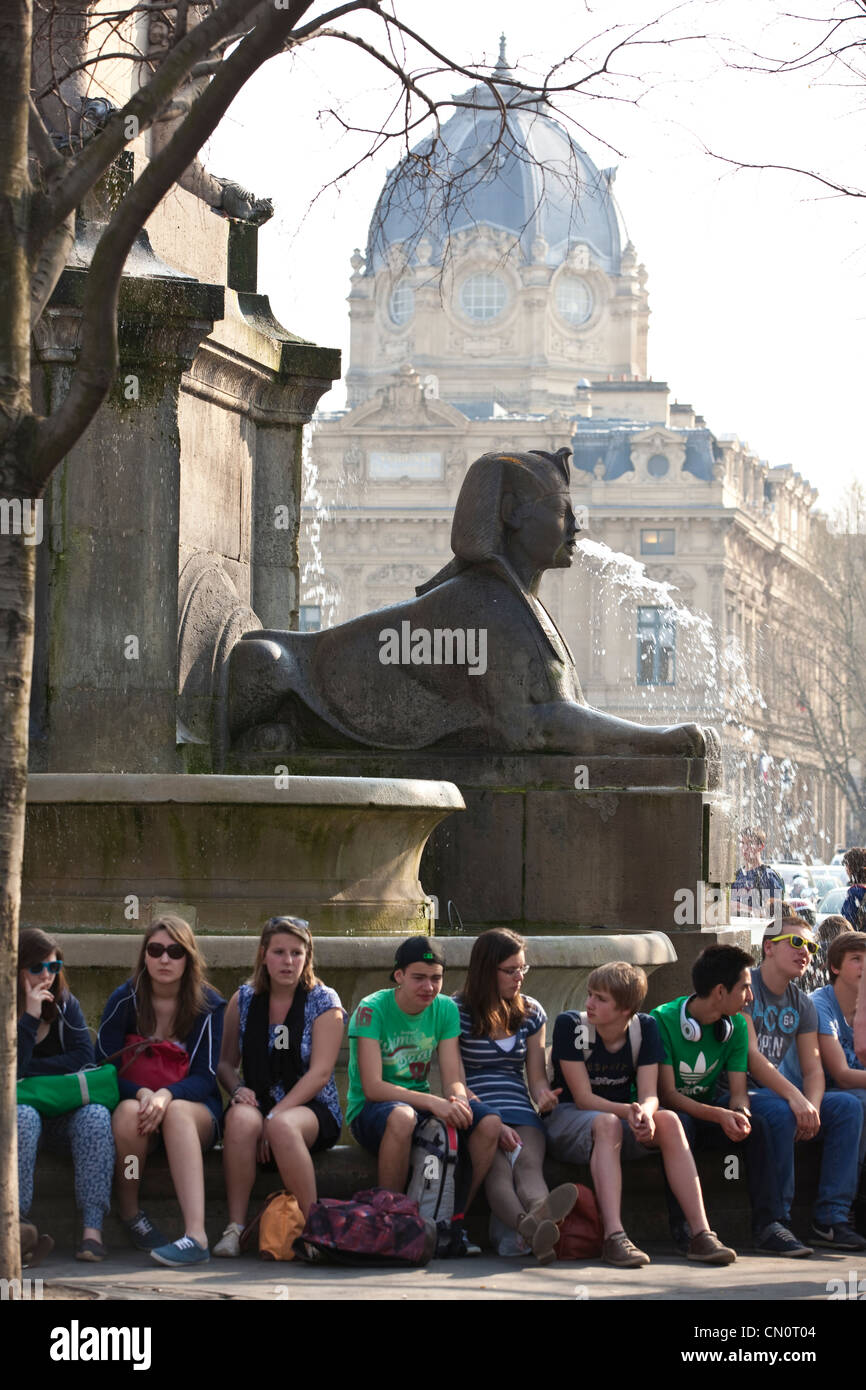 Französische Studenten sitzen unter der La Fontaine du Palmier in Place du Châtelet, Paris, Frankreich. Stockfoto