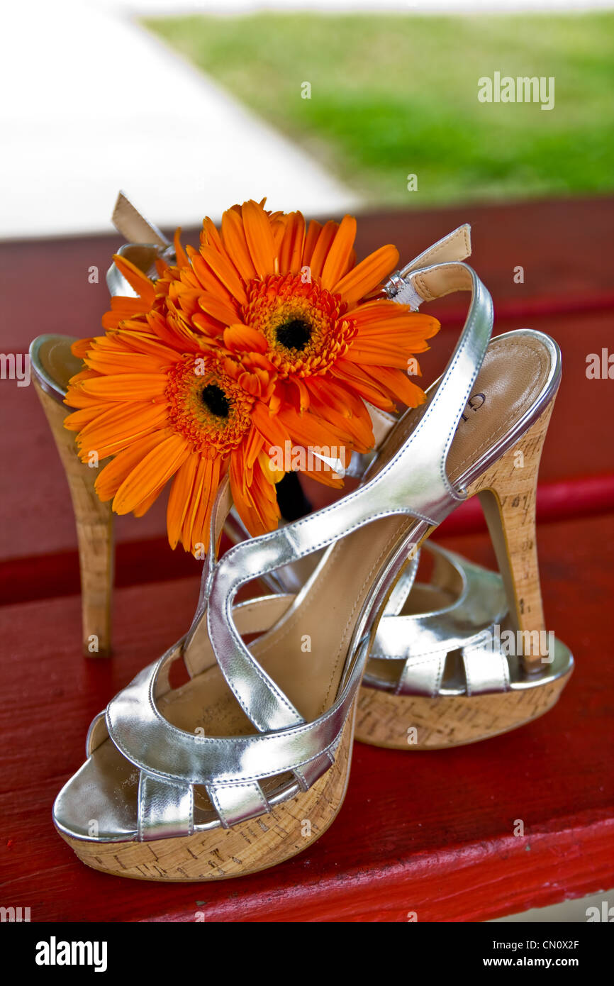 Die Braut auszog ihre Schuhe um an den Strand in ihrem Hochzeitskleid für Bilder hinterlässt einen kleinen Blumenstrauß heruntergekommen Stockfoto