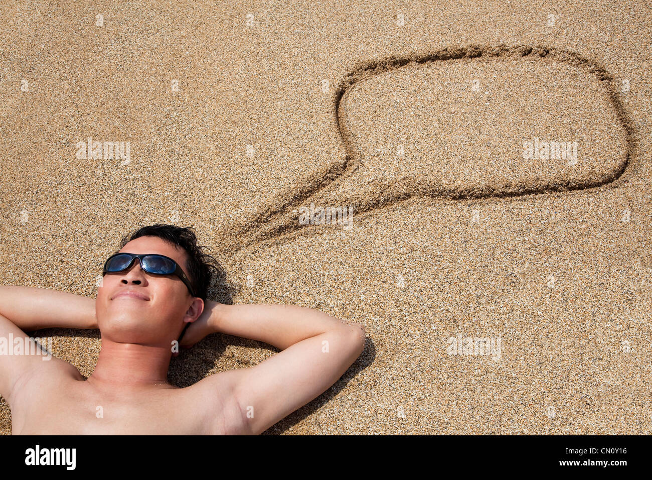 lächelnde junge Mann liegend auf den Strand und Dialog-symbol Stockfoto