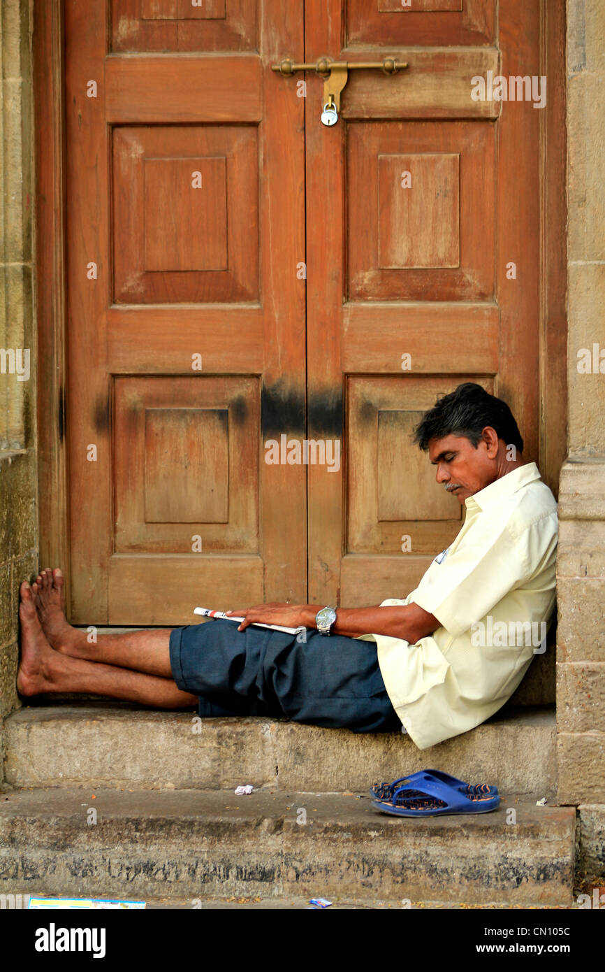 Indischer Mann schlafen durch eine Holztür in Kala Ghoda, Mumbai, Indien Stockfoto