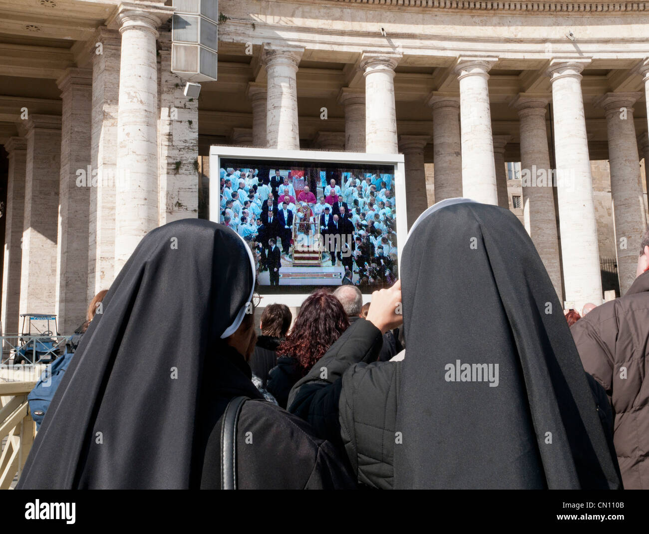 Zwei Nonnen, die vor dem Fernseher mit Papst Benedikt auf einem großen TV-Bildschirm außerhalb Str. Peters Basilica in Rom, Italien Stockfoto