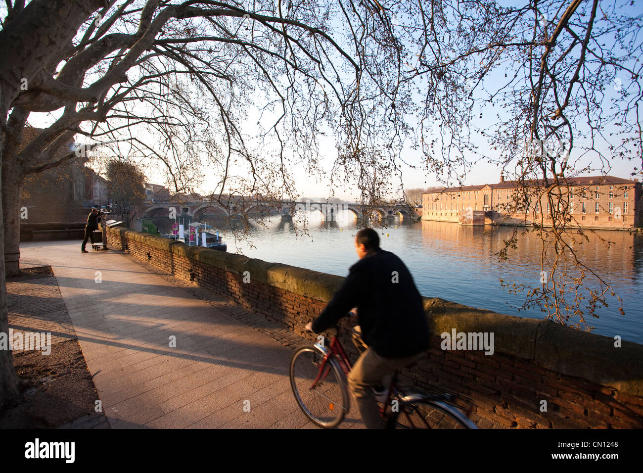 Radfahrer entlang La Garonne frühmorgens am Quai Lucien Lombard mit Hotel Dieu St Jaques in Ferne, Toulouse, Frankreich. Stockfoto