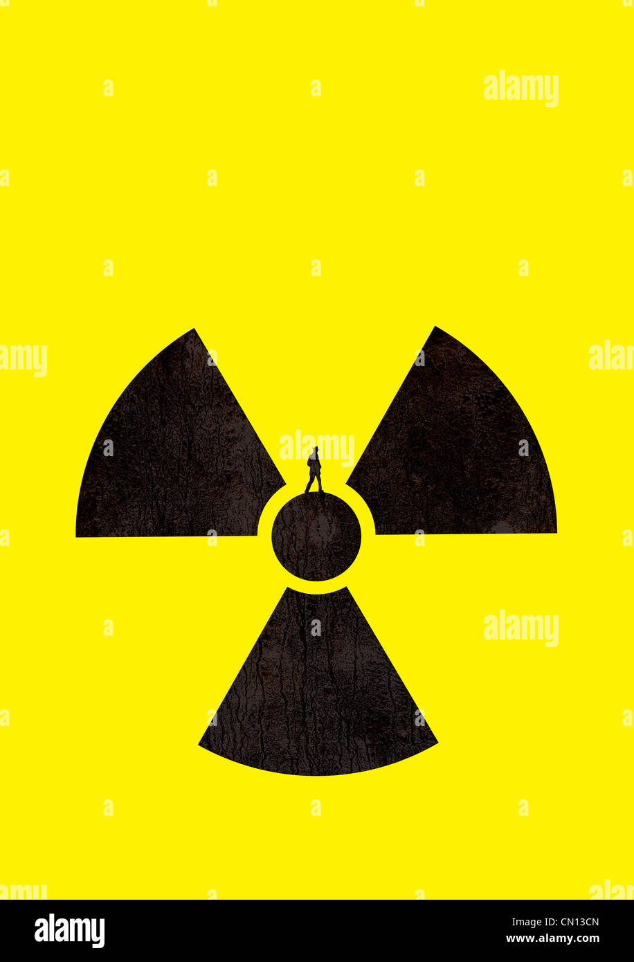 Mann auf einem radioaktiven Symbol. Der Mann und Symbol sind Silhouetten auf einem gelben Hintergrund. Stockfoto