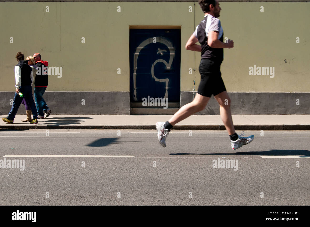 Ein Jogger beim Vienna City Marathon läuft eine Möglichkeit während Passanten in die entgegengesetzte Richtung gehen. Stockfoto