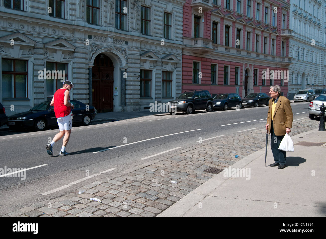 Ein älterer Herr Uhren einen Jogger vorbei beim Vienna City Marathon laufen. Stockfoto