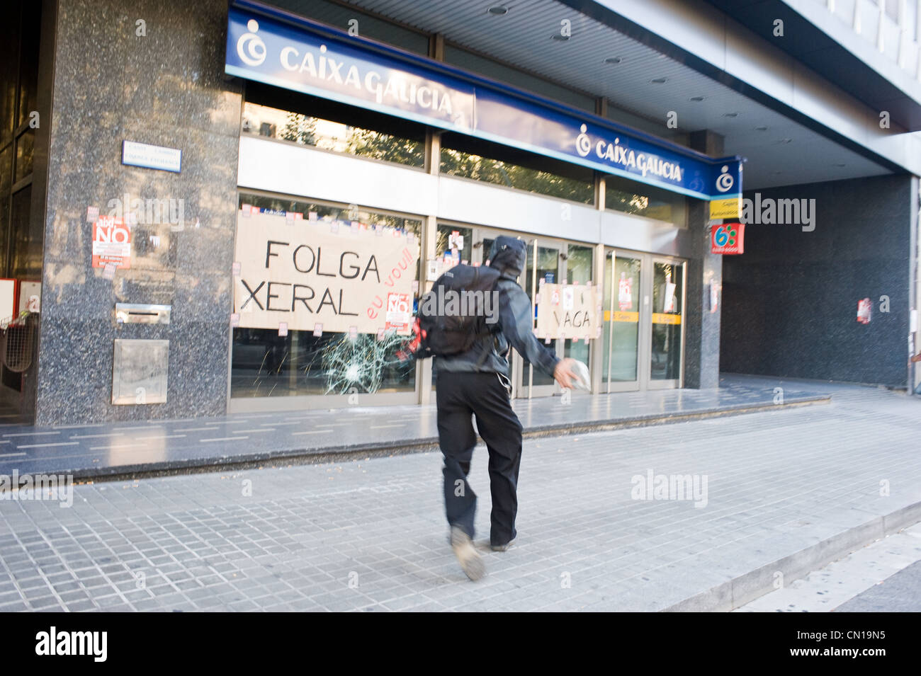 Demonstrant Angriff auf eine Bankfiliale während des Generalstreiks 2010 in Barcelona, Spanien. Stockfoto