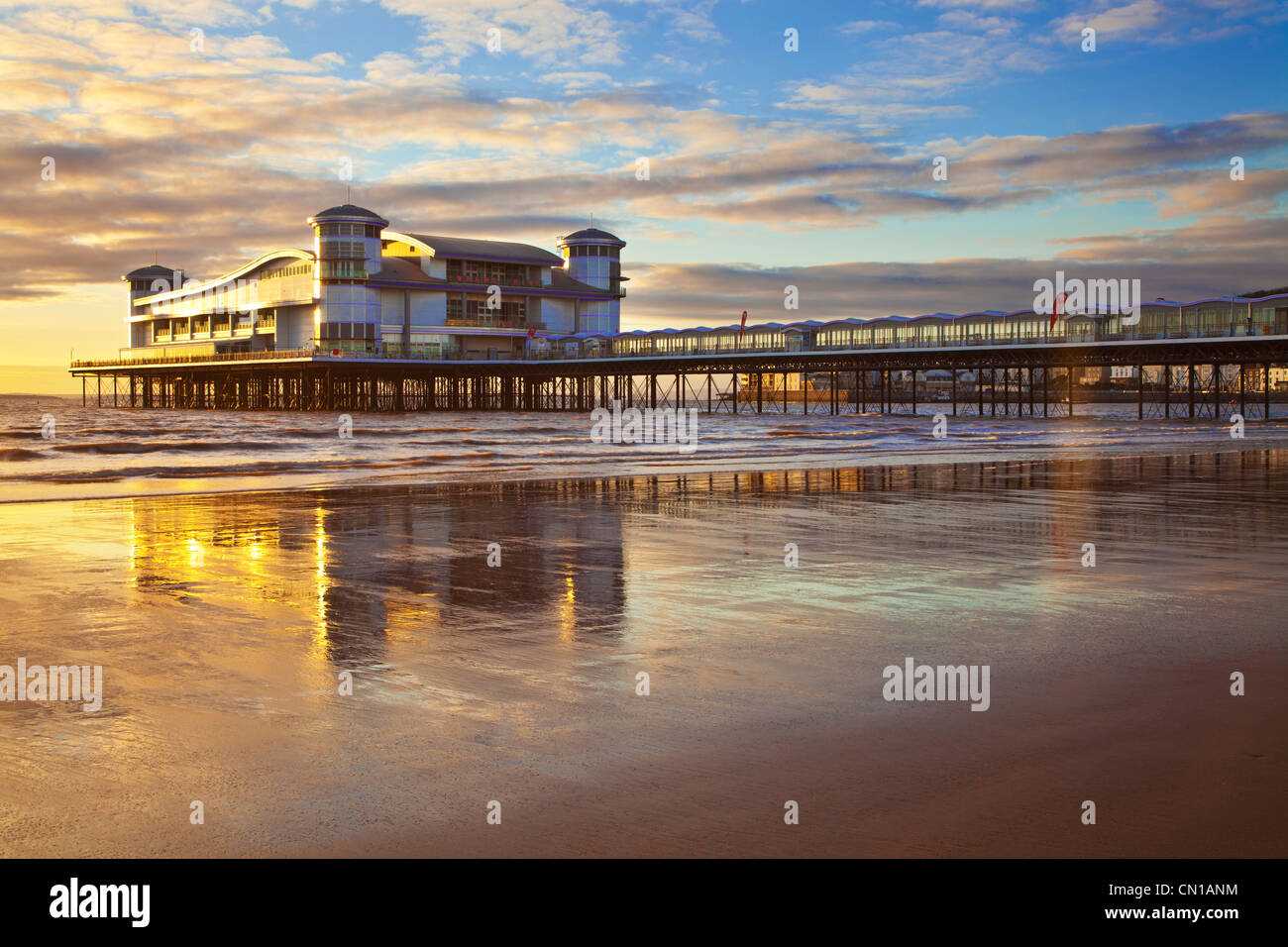 Goldene Abendlicht fällt auf der Grand Pier am Weston-Super-Mare, Somerset, England, UK Eflected im nassen Sand an den hohen Gezeiten. Stockfoto