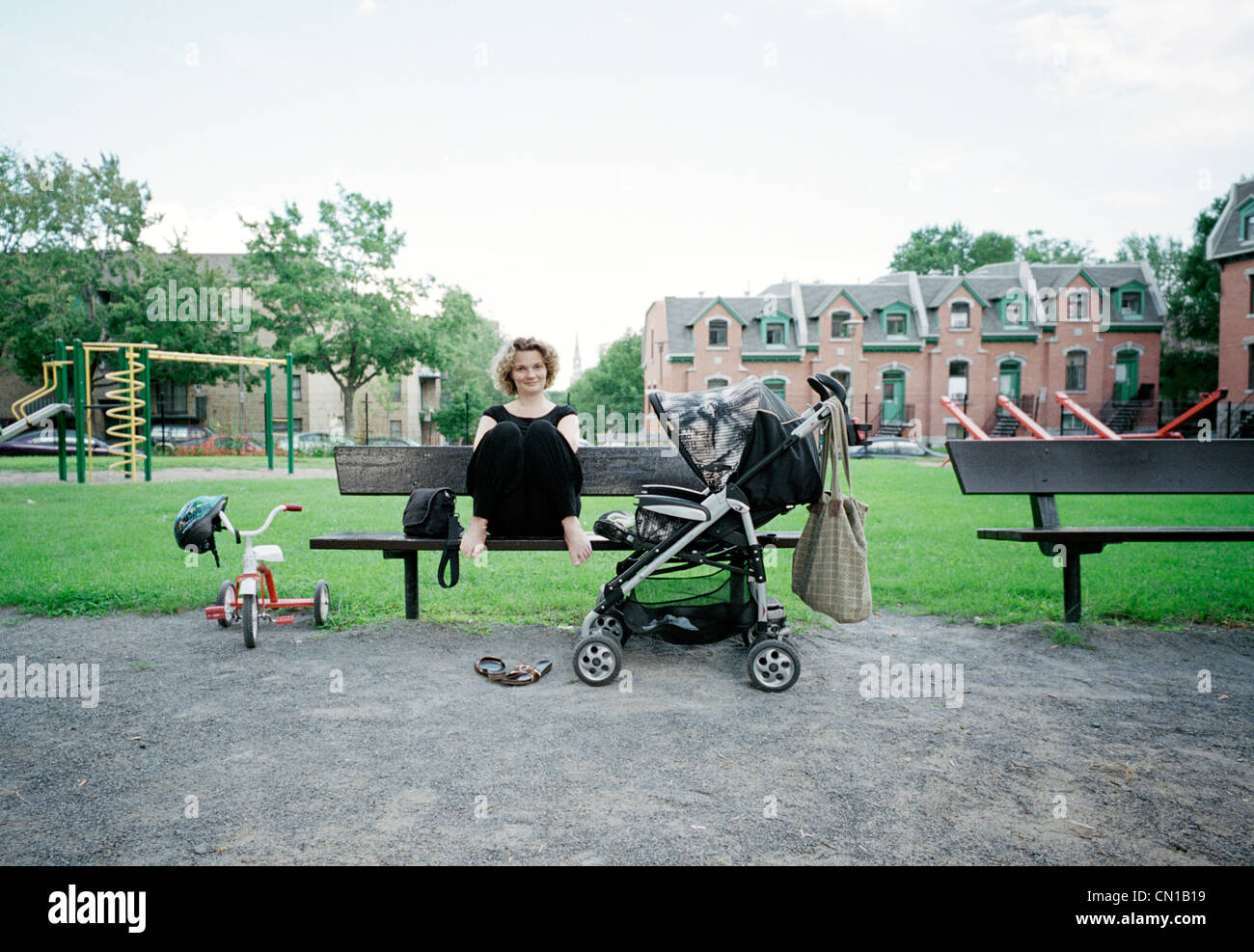 Frau auf einer Bank in einem Park mit einem Kinderwagen, Montreal, Quebec Stockfoto