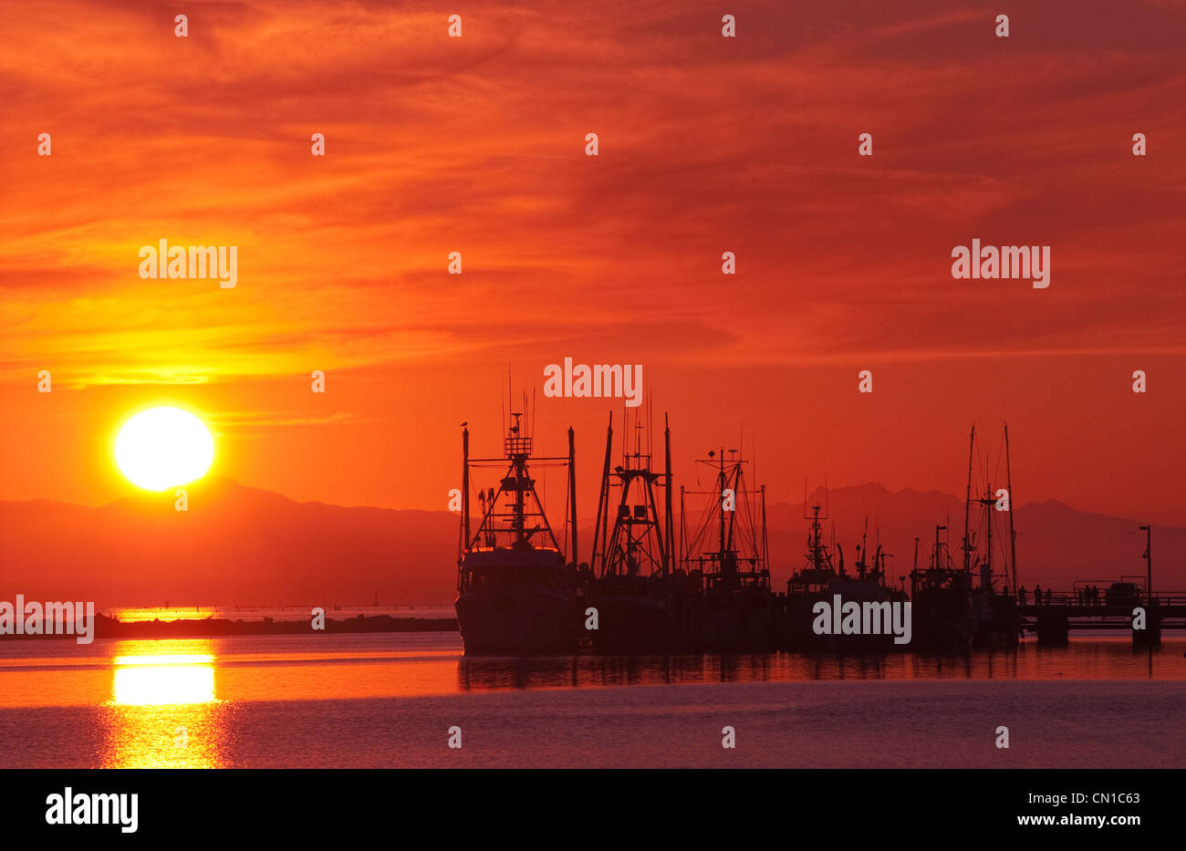 Fischereifahrzeuge bei Sonnenuntergang mit Vancouver Island Mountains im Hintergrund, Richmond, Britisch-Kolumbien Stockfoto