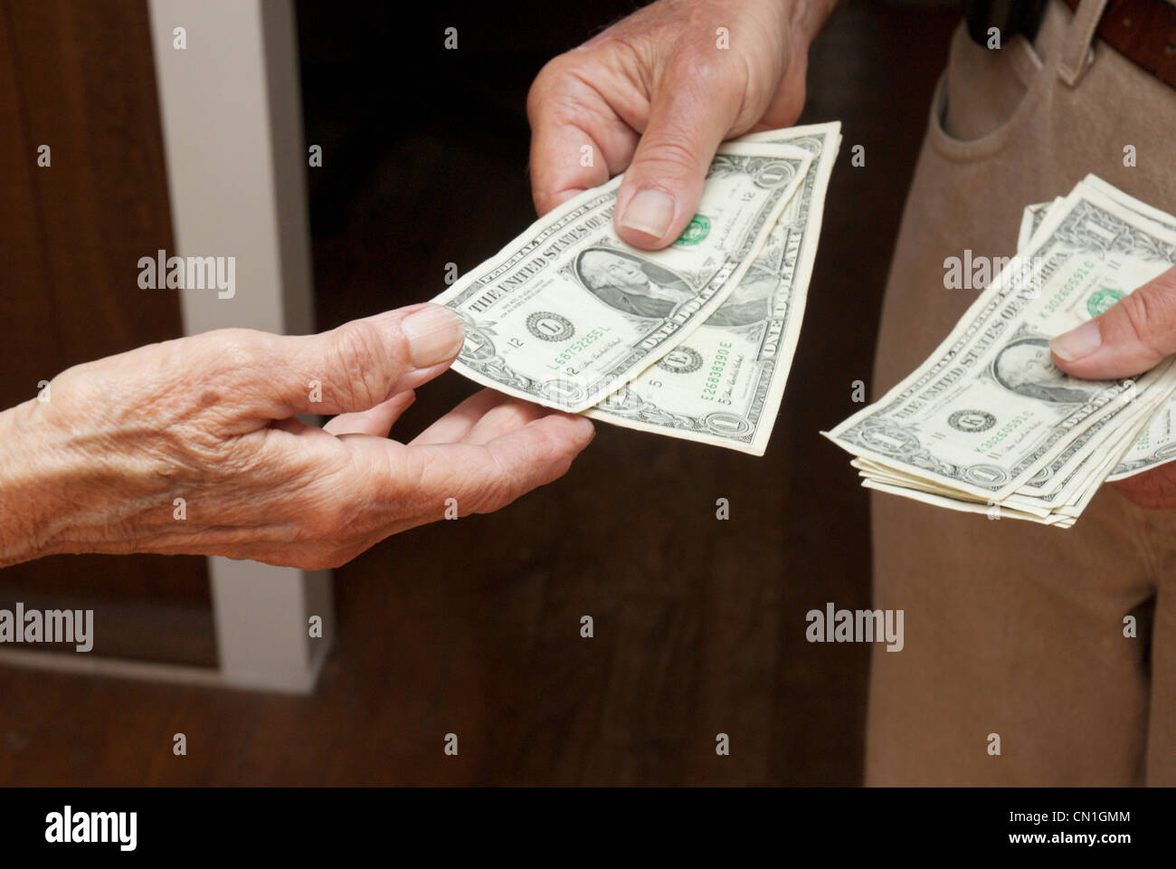 Älterer Mann Übergabe Dollarnoten an Frau Stockfoto