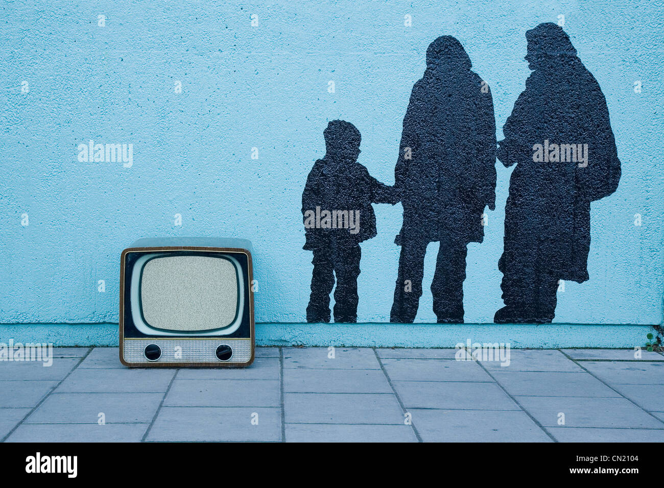 Retro-TV durch blaue Wand mit Wandbild von drei Personen Stockfoto