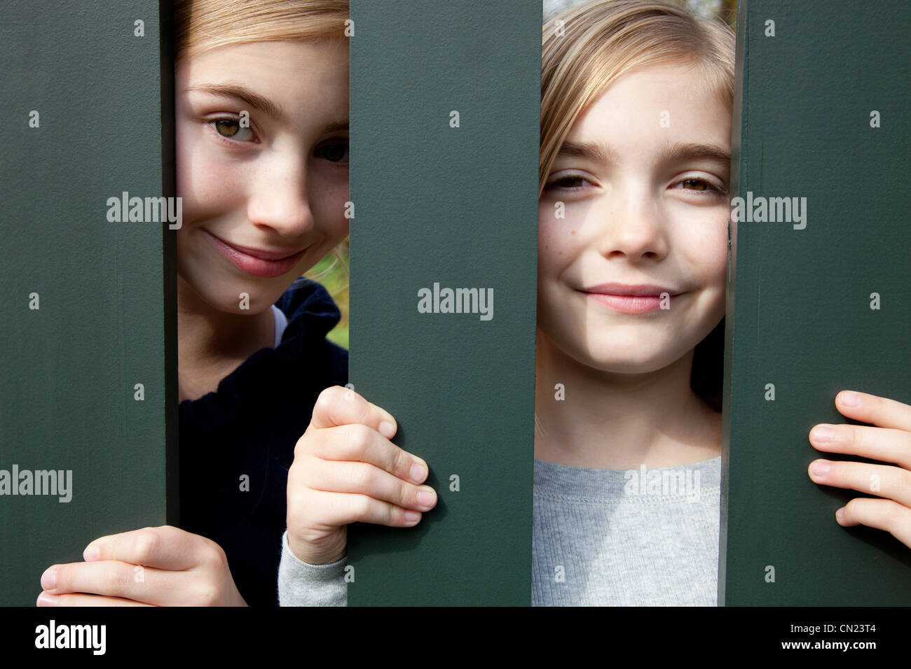 Zwei lächelnde Mädchen hinter Zaun Stockfoto