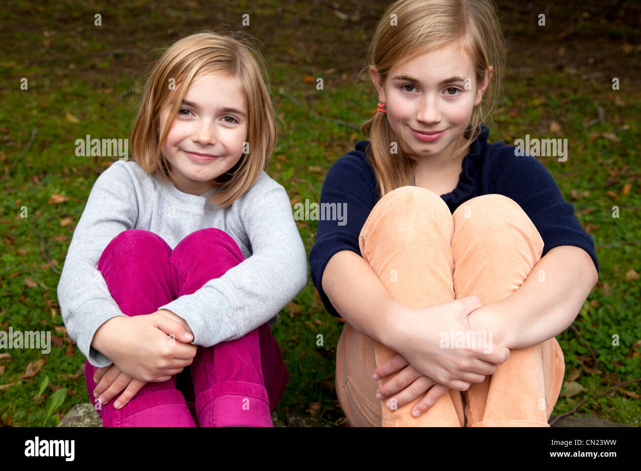Zwei lächelnde Mädchen mit Armen Beine umwickelt Stockfoto