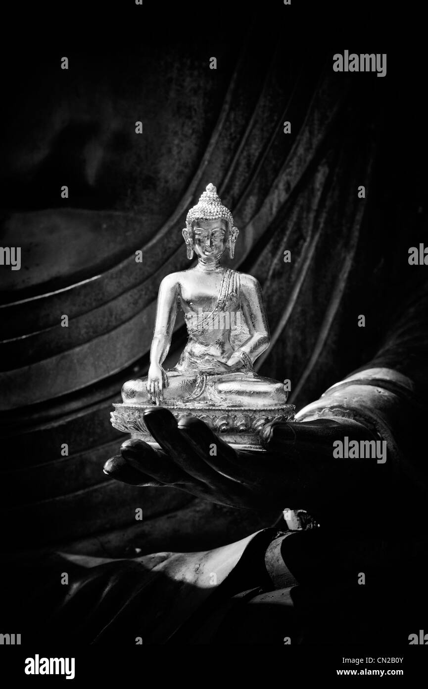 Buddha-Statue auf der Seite von einem sehr großen Buddha-Statue sitzt. Monochrom Stockfoto