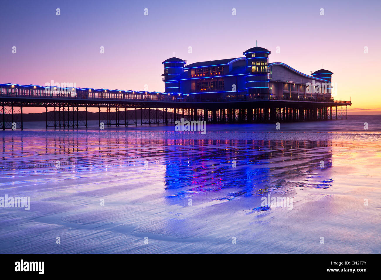 Dämmerung über dem Grand Pier bei Weston-Super-Mare, Somerset, England, UK spiegelt sich in dem nassen Sand des Strandes bei Flut. Stockfoto