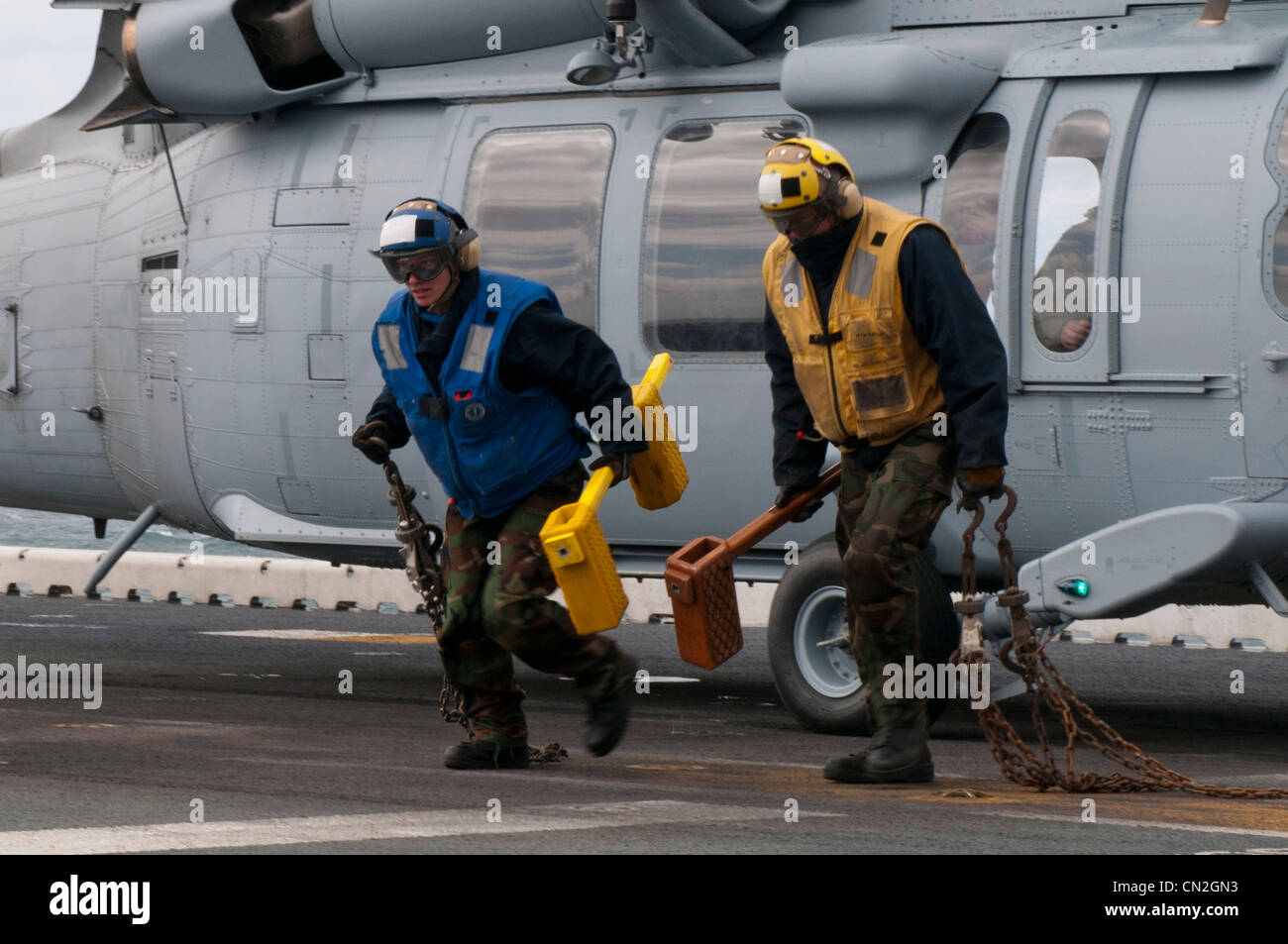 Die Flugbootsfreunde laufen vor einem MH-60S Knight Hawk Hubschrauber, nachdem sie Keile und Ketten entfernt haben und das Flugzeug für den Start auf dem Flugdeck des amphibischen Sturmschiffs USS Kearsarge (LHD 3) bereit gemacht haben. Kearsarge führt derzeit ein Training der Afloat Training Group 1.4 in der Grundphase durch. Stockfoto