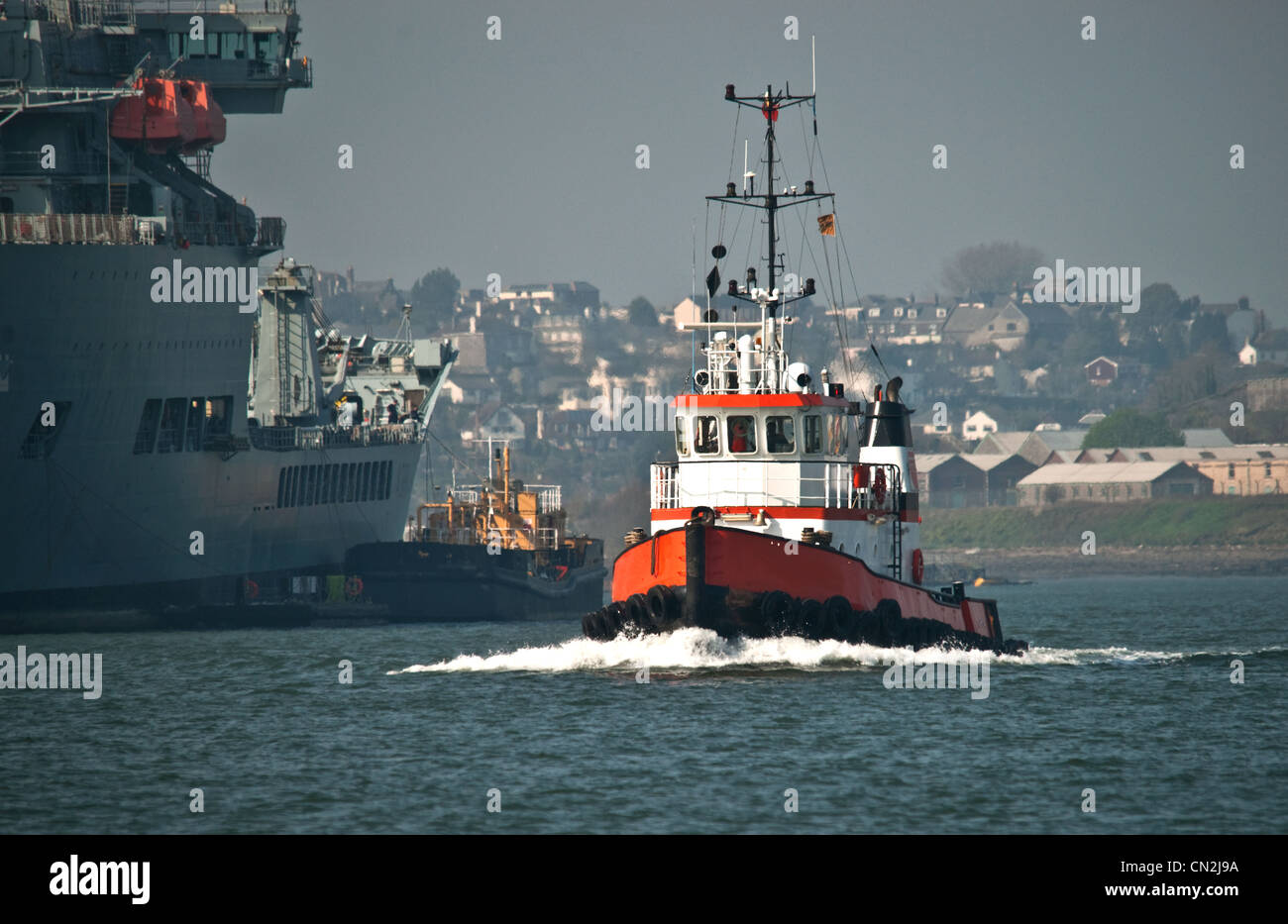 Ein kleines Boot / segeln vorbei an einem Royal Fleet Auxiliary Schiff im Fluss Tamar zu zerren Stockfoto