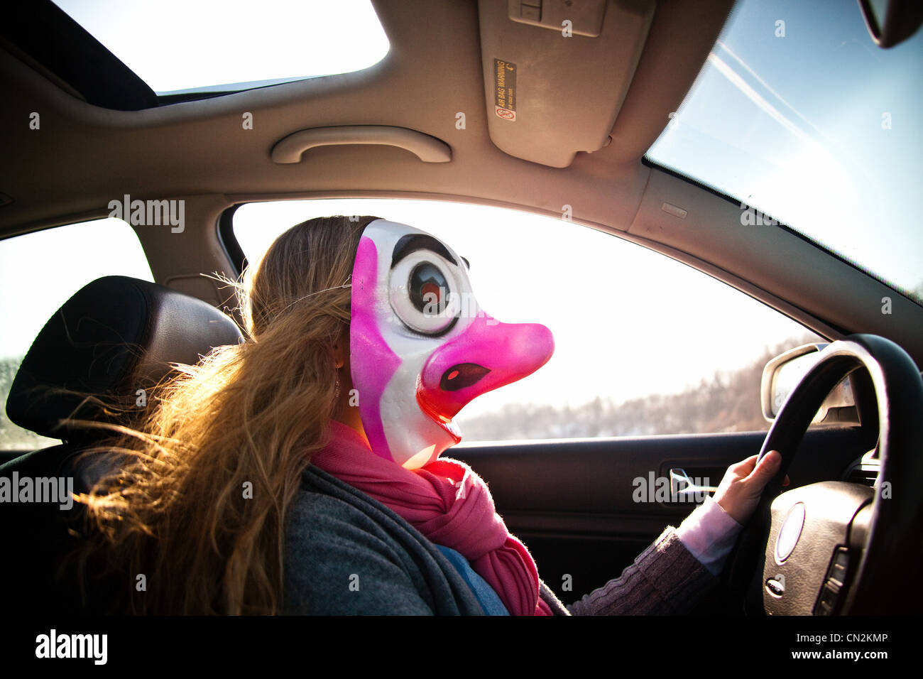 Frau Auto mit Clownsmaske Stockfoto