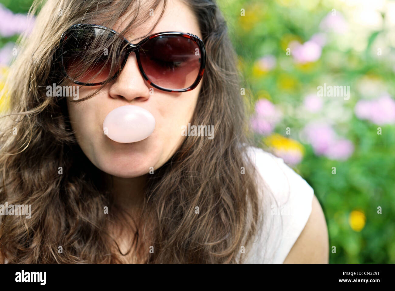 Junge Frau, die Seifenblase mit Kaugummi Stockfoto