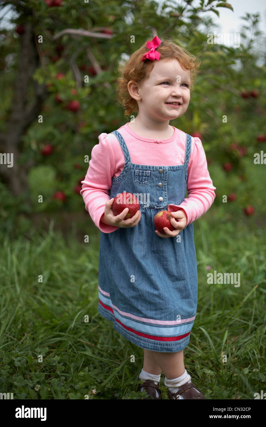 Mädchen stehen im Obstgarten mit Äpfeln Stockfoto