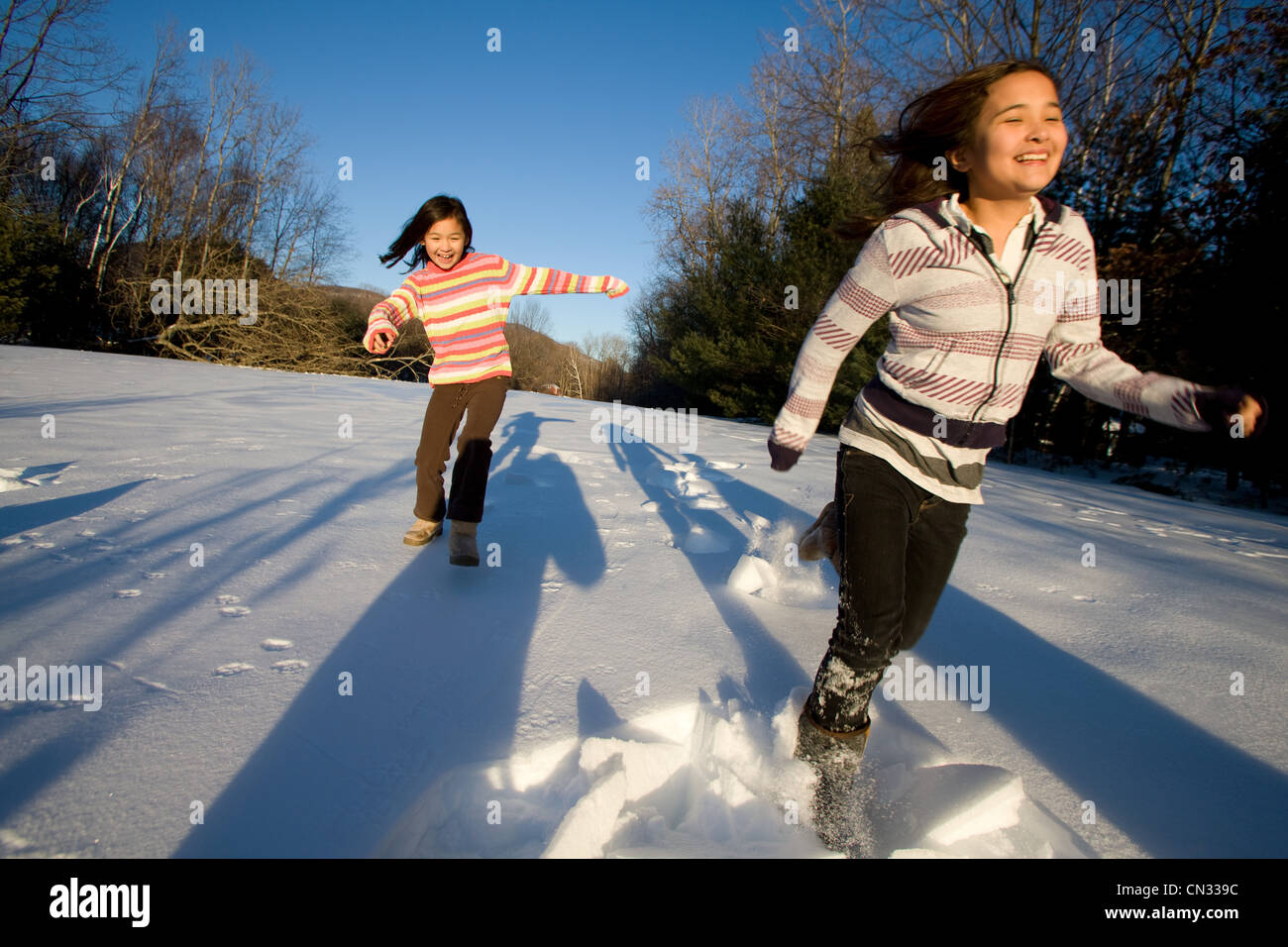 Zwei Mädchen laufen im Schnee Stockfoto