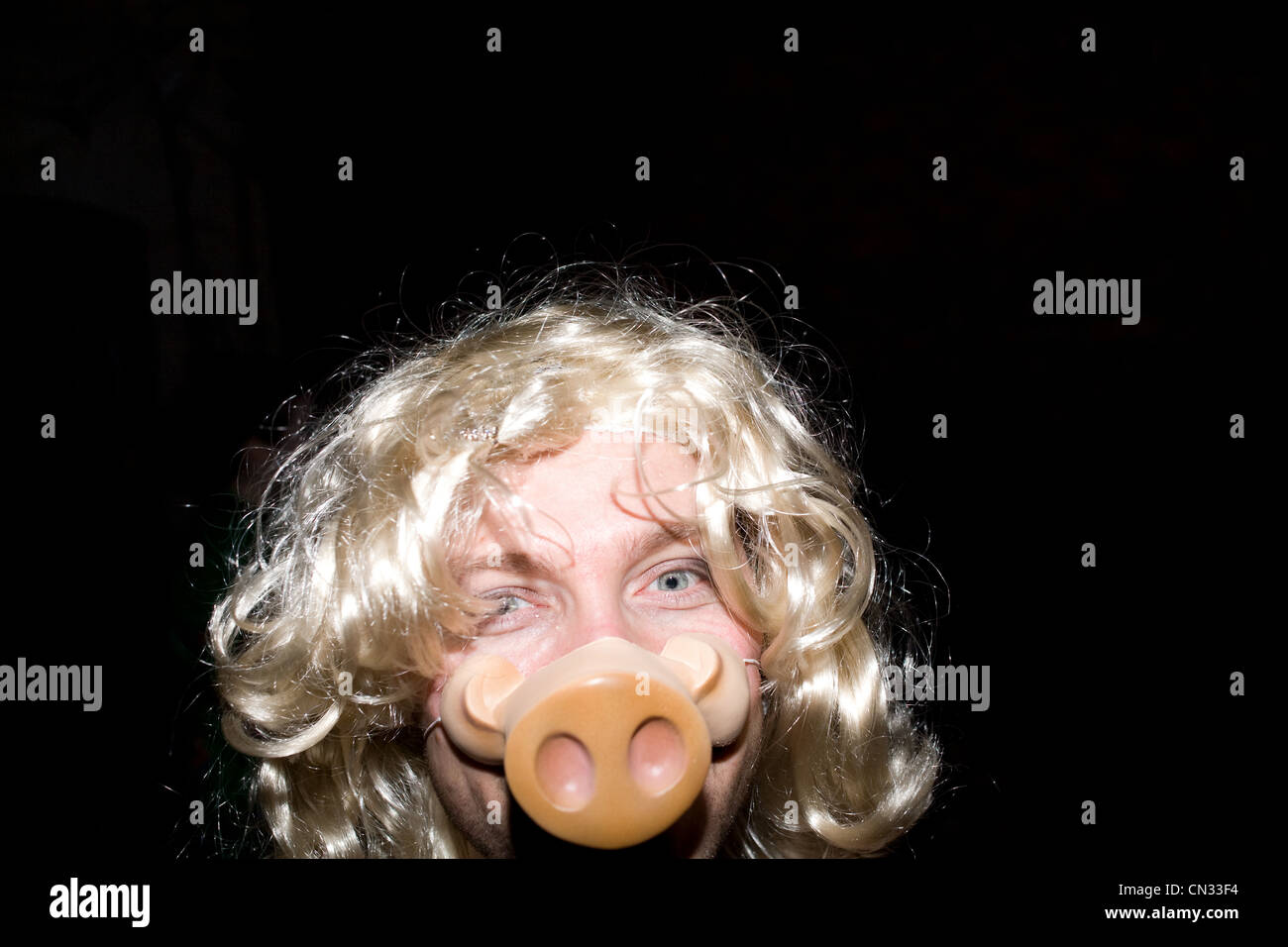 Mann mit blonder Perücke und des Schweines Schnauze Maske Stockfoto